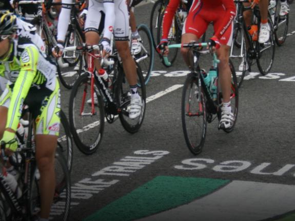 Road cyclists passing over the 7 Stanes logo applied to the road using large stencils