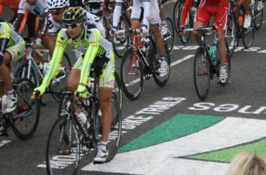 Road cyclists passing over the 7 Stanes logo applied to the road using large stencils