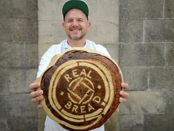 Baker holding bread stencilled with Real Bread logo
