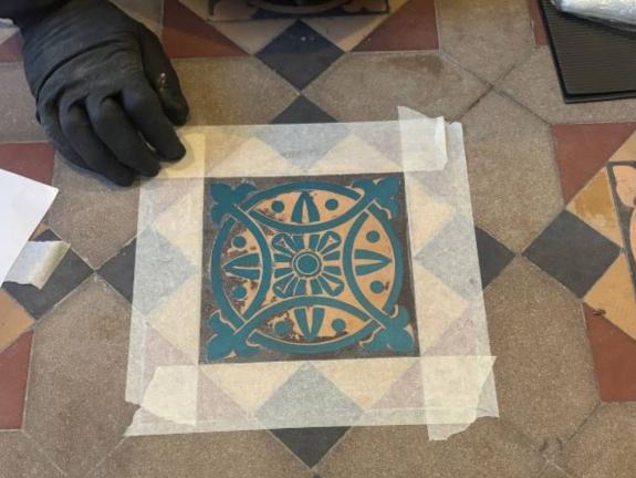 Stencil taped over a Victorian tile during the restoration process