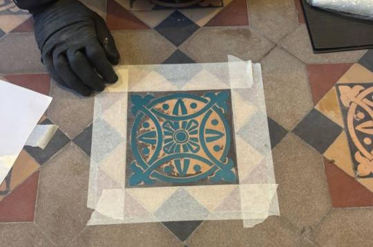 Stencil taped over a Victorian tile during the restoration process