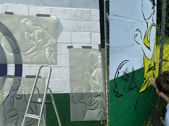 Man painting Wall Mural for a Tennis Club using stencils