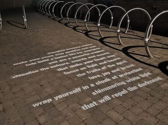 Short poem stencilled onto city street in white letters