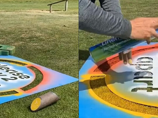 Social distancing message being applied to grass with chalk paint