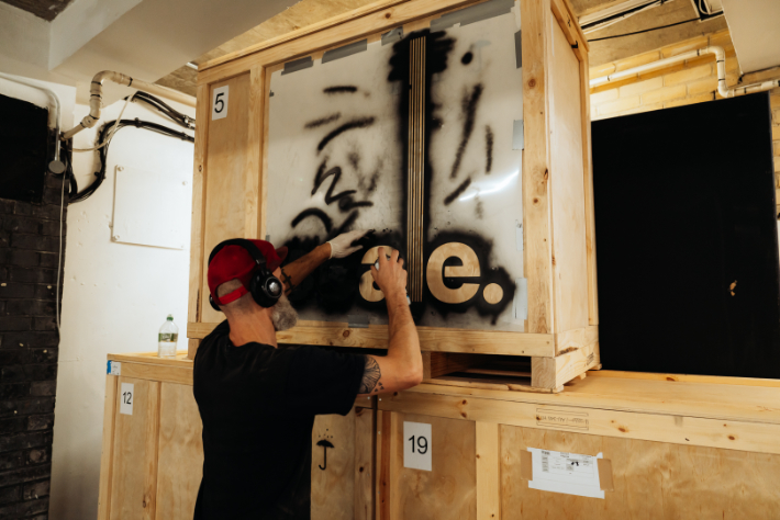 Spray painting Scale logo on wooden crates using custom stencils