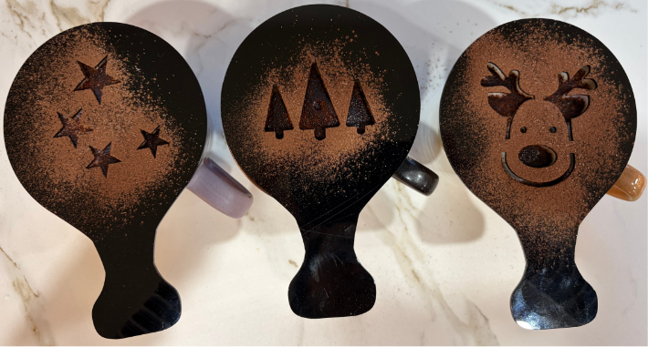 Three late coffees with stencils dusted with coco powder